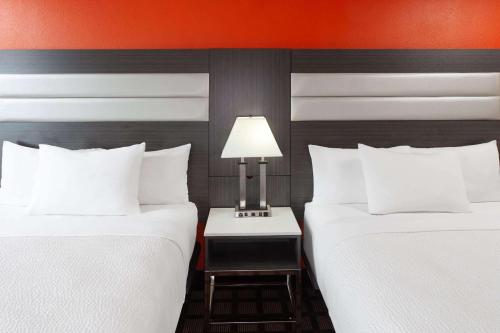 a hotel room with two beds and a table with a lamp at AmericInn by Wyndham Hudson in Hudson