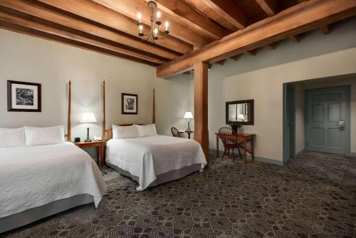 a bedroom with two beds and a table and chairs at The Historic Brookstown Inn, Trademark Collection by Wyndham in Winston-Salem