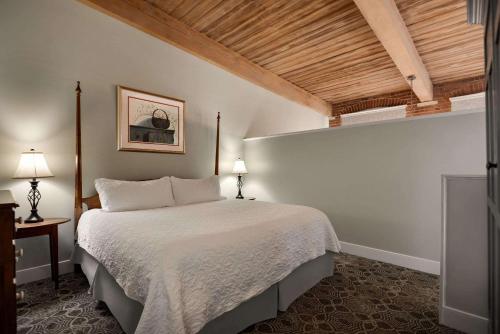 a bedroom with a bed and a wooden ceiling at The Historic Brookstown Inn, Trademark Collection by Wyndham in Winston-Salem