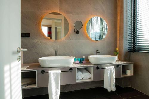 a bathroom with two sinks and two mirrors at Ramada by Wyndham Diyarbakir in Diyarbakır