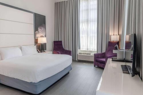 a hotel room with a bed and two purple chairs at TRYP by Wyndham Savannah in Savannah
