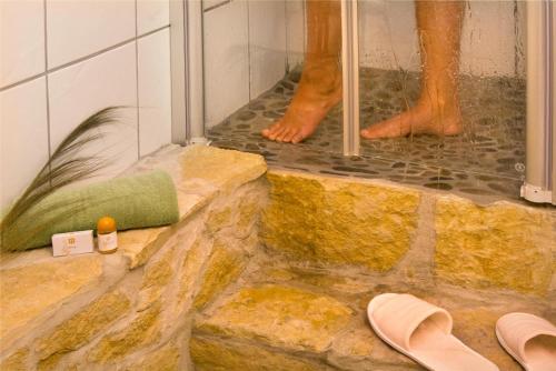 a man standing in a shower with his feet at Hotel-Bistro-Europa in Merchweiler