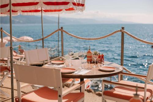 a table with chairs and wine glasses on the beach at The Maybourne Riviera, Maybourne in Roquebrune-Cap-Martin