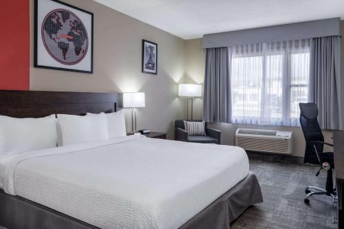 a hotel room with a large bed and a chair at Ramada by Wyndham Thunder Bay Airlane Hotel in Thunder Bay