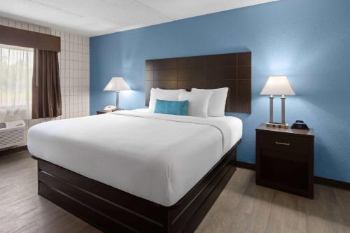 a large bed in a hotel room with blue walls at Baymont Inn and Suites by Wyndham Farmington, MO in Farmington