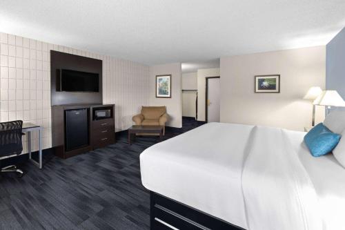 a hotel room with a large bed and a chair at Baymont Inn and Suites by Wyndham Farmington, MO in Farmington
