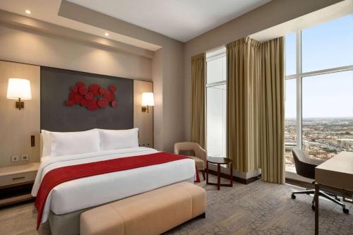 a hotel room with a bed and a large window at Ramada by Wyndham Riyadh King Fahd Road in Riyadh