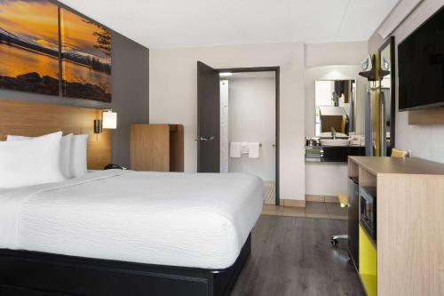 a hotel room with a large bed and a bathroom at Days Inn by Wyndham Columbus Worthington in Columbus