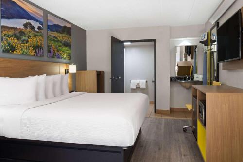 a hotel room with a large bed and a television at Days Inn by Wyndham Columbus Worthington in Columbus