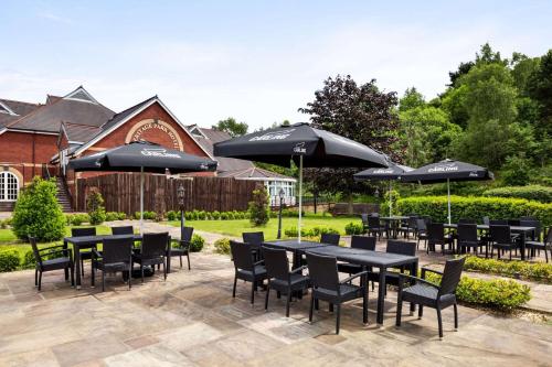 a patio with black tables and chairs and umbrellas at Heritage Park Pontypridd, Trademark Collection by Wyndham in Pontypridd
