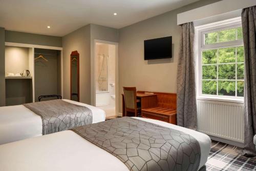 a hotel room with two beds and a window at Heritage Park Pontypridd, Trademark Collection by Wyndham in Pontypridd