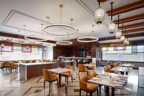 a restaurant with tables and chairs and chandeliers at Ramada Encore by Wyndham Udaipur Roopnagar in Udaipur