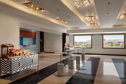 a lobby of a hotel with tables and windows at Ramada Encore by Wyndham Udaipur Roopnagar in Udaipur