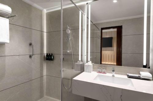 a bathroom with a sink and a shower with a mirror at Ramada Encore by Wyndham Udaipur Roopnagar in Udaipur