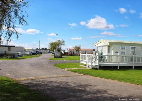 a house with a white fence next to a street at The Chase Holiday Park in Ingoldmells