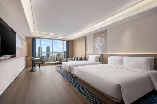 a hotel room with two beds and a television at Microtel by Wyndham Qingdao Huangdao in Qingdao