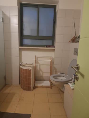 a bathroom with a toilet and a window at בית פרטי לחופש משפחתי in Bayit Wegan
