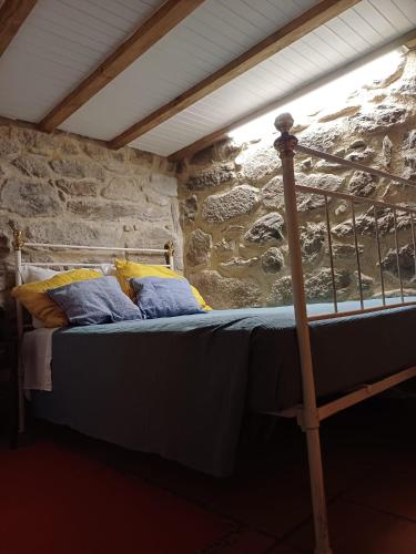 a bed in a room with a stone wall at Moinho do Formigal in Valença