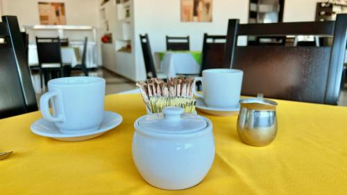 a yellow table with cups and utensils on it at Hotel Renzzo in Río Verde