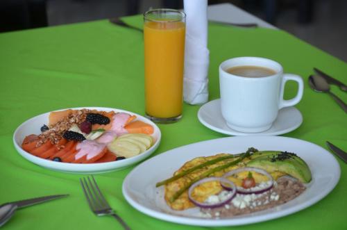 a green table with two plates of food and a cup of coffee at Hotel Renzzo in Río Verde