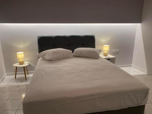 a bedroom with a large bed with two lamps at Alyzia Apartment in Xylokastro