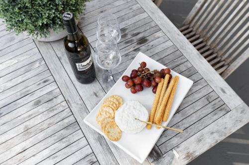 a plate of food with grapes and crackers and a bottle of wine at Rock Salt by Experience Jervis Bay in Huskisson