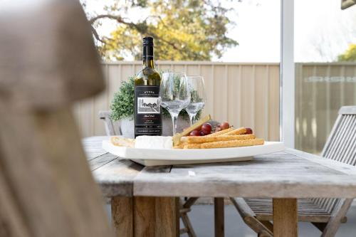 a table with a bottle of wine and a plate of food at Rock Salt by Experience Jervis Bay in Huskisson