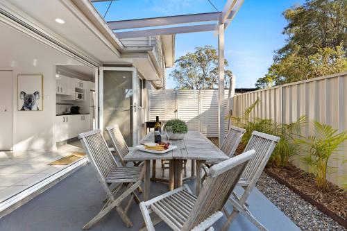 a patio with a wooden table and chairs at Rock Salt by Experience Jervis Bay in Huskisson