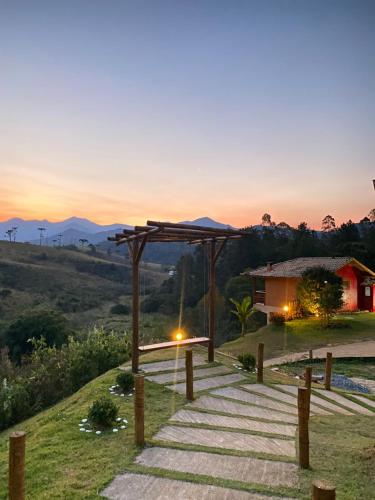 a pathway leading to a house with a sunset in the background at Pousada Chales Joao de Barro in Visconde De Maua