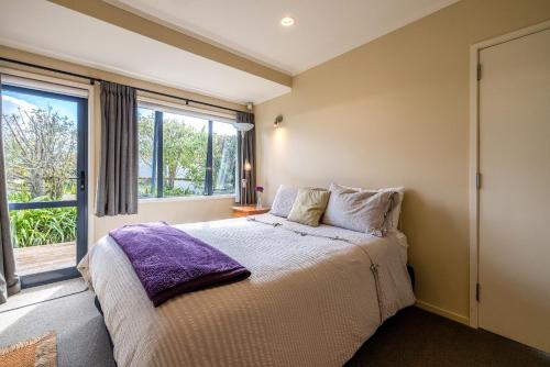 a bedroom with a bed and a large window at Double Bay Views, Oneroa - Be My Guest in Blackpool