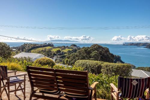 two chairs sitting on a patio overlooking the water at Double Bay Views, Oneroa - Be My Guest in Blackpool