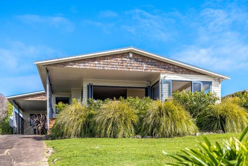 a house with tall grass in the front yard at Double Bay Views, Oneroa - Be My Guest in Blackpool