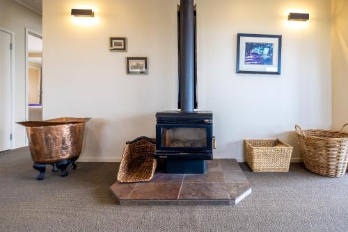 a wood stove in a room with wicker baskets at Double Bay Views, Oneroa - Be My Guest in Blackpool