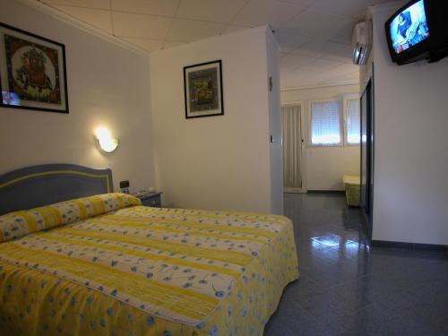 Hotel Crystal Park في فيناروس: غرفة نوم بسرير اصفر وتلفزيون