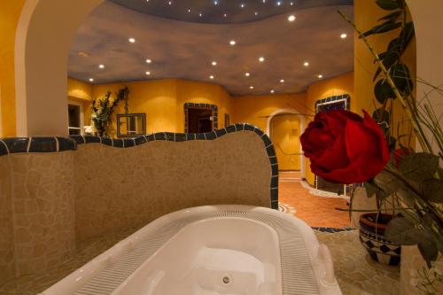 e bagno con vasca e rosa rossa. di Der Brückenhof Ramsau a Ramsau am Dachstein