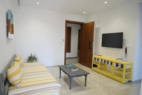a living room with a couch and a tv at Le soleil jaune in Sfax