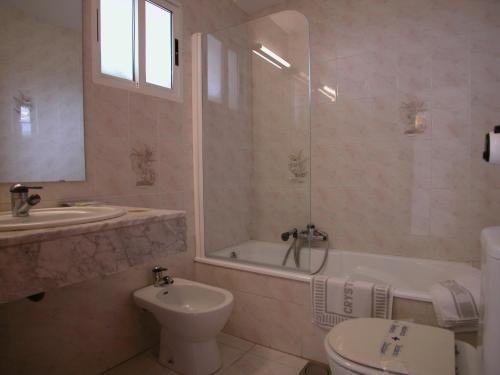 a bathroom with a toilet and a tub and a sink at Hotel Crystal Park in Vinaròs