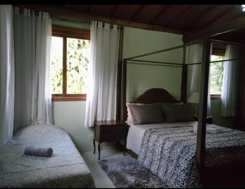 a bedroom with a canopy bed and a window at Quinta da Pedra do Elefante in Petrópolis