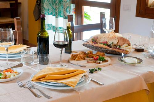 a table topped with plates of food and wine glasses at Hotel I Menhirs in Annunziata