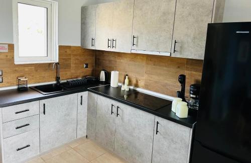 a kitchen with white cabinets and a black refrigerator at Saladi Beach House in Didyma