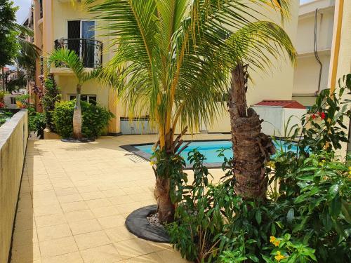 a courtyard with palm trees and a swimming pool at Avenue soleil sur mer flic en flac in Flic-en-Flac