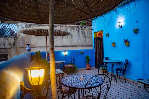a patio with tables and chairs and a blue wall at Dar Lalamoune in Fès
