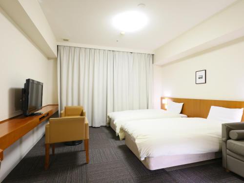 a hotel room with two beds and a tv at Dormy Inn Kanazawa Natural Hot Spring in Kanazawa