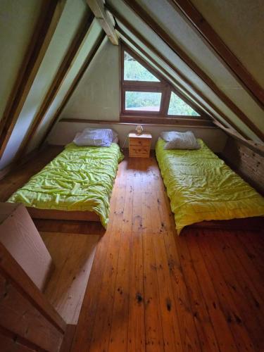 two beds in a attic bedroom with a window at Idylissches Ferienhäusle im Thüringer Wald in Suhl