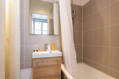 une salle de bain avec un lavabo, une baignoire et un miroir dans l'établissement Sevres Cosy studio, à Paris