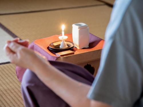 a person sitting in bed with a table with a candle at Togakubo in Isehara