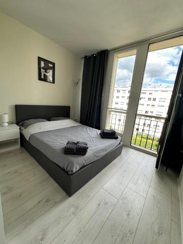 Un dormitorio con una cama y una ventana grande. en Appart ensoleillé à Boulogne Billancourt, en Boulogne-Billancourt