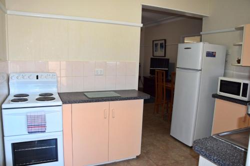 y cocina con fogones blancos y nevera. en Clarkes Flat 3, en South West Rocks