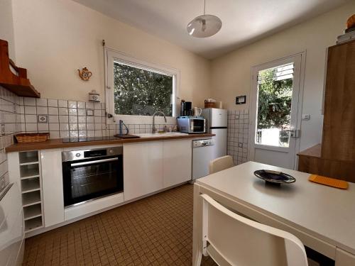 une cuisine avec des appareils blancs et une table avec des chaises dans l'établissement Maison lumineuse avec jardin près de la plage - 4 couchages, quartier calme, St Brévin L'Océan - FR-1-364-136, à Saint-Brévin-les-Pins
