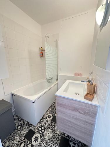 une salle de bain blanche avec une baignoire et un lavabo dans l'établissement Appart ensoleillé à Boulogne Billancourt, à Boulogne-Billancourt